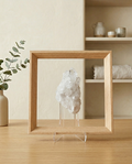 Clear Quartz Cluster in a Light Wood Floating Frame on a wooden surface with a neutral background